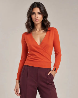 Close-up of the orange Alba Arancione sweater showing the crossover V-neck front, long sleeves and ribbed hem.