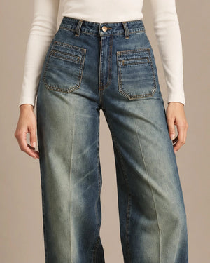 Close-up of Amber blue jeans showing the high waistband, button fastening and stitched front patch pockets.