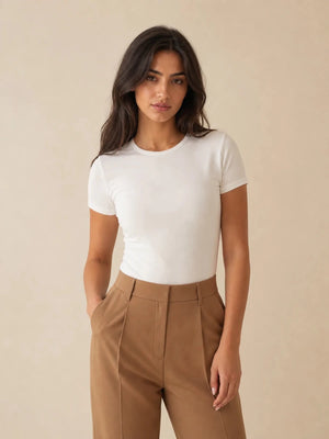 White crew-neck short-sleeve top tucked into camel trousers, front view