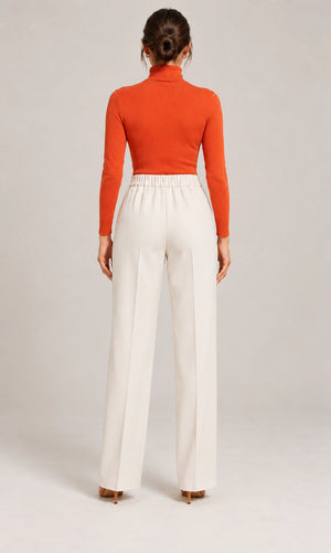 Full-length rear view of the ivory Elisa Panna tailored trousers, styled with an orange long-sleeve top.