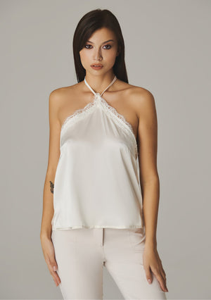 Front view of the plain ivory halter top styled with ivory trousers
