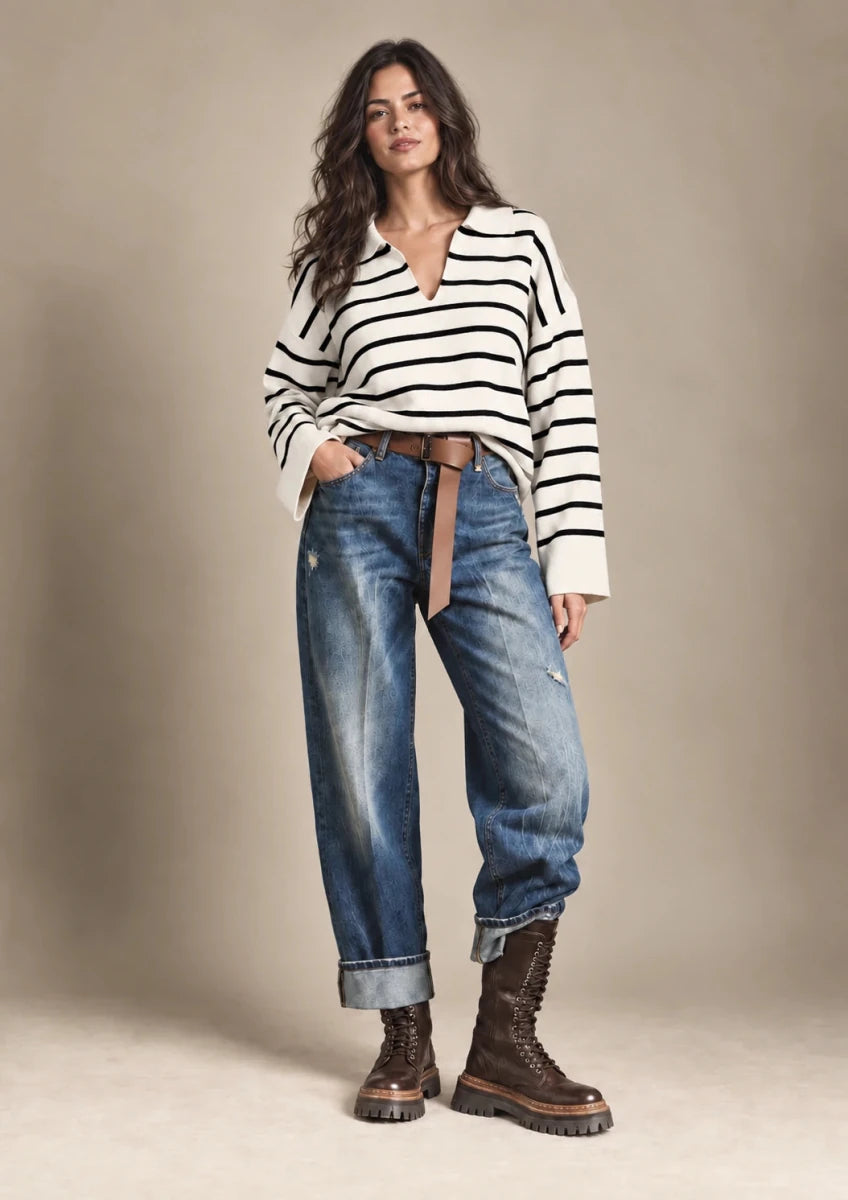 Front view of the Rossana cream knit sweater with black horizontal stripes, long sleeves and an open polo-style collar, worn with jeans.