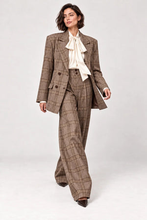 Rosalinda brown check blazer and matching Hope wide-leg trousers shown walking, styled with an ivory bow-neck blouse.