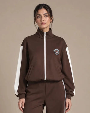 Close-up of Leila Moro track jacket showing the high collar, front zip, white sleeve stripes and chest badge.