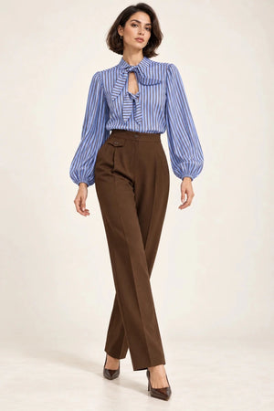 Full-length view of a model wearing a blue and brown striped bow-tie shirt with brown tailored trousers.