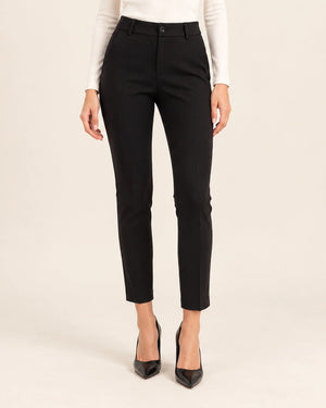 Front detail of black tailored ankle-length trousers showing the waistband and tapered legs, with arms at the sides.
