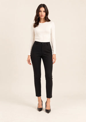Full-length front view of black tailored ankle-length trousers, worn with an ivory top, with arms at the sides.