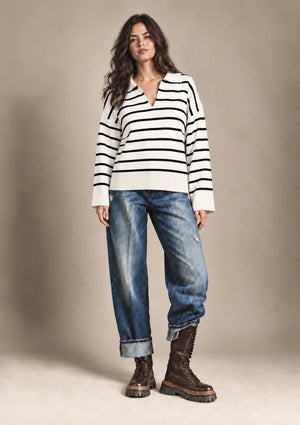 Full-length front view of Rossana cream-and-black striped sweater worn untucked with blue jeans.