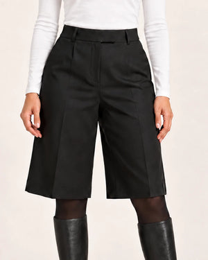 Close-up of Shorts Pinces Nero black pleated shorts with a white top and black tights