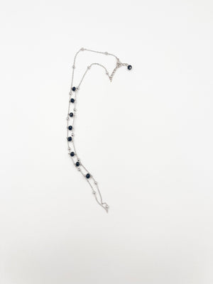 Silver-tone double-chain jewellery laid flat, showing dark faceted beads, small round metal beads and an extension clasp.