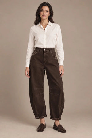 Full-length view of a model wearing brown barrel-leg trousers with a white shirt and brown loafers.