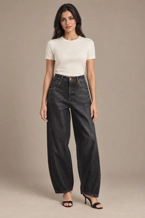Full-length front view of dark-wash Zaira barrel-leg jeans, styled with an ivory T-shirt and black heeled sandals.