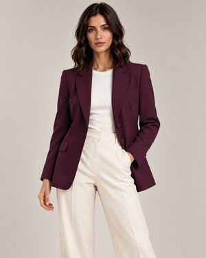 Front styling view of the Adelaide Bordeaux tailored blazer with notched lapels and flap pockets, worn open over an ivory top and trousers.