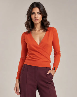 Close-up of the orange Alba Arancione sweater showing the crossover V-neck front, long sleeves and ribbed hem.