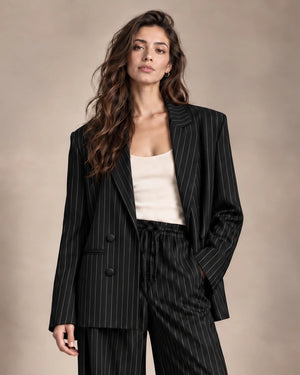 Close-up of the Alba black pinstripe double-breasted blazer with notched lapels, styled with matching trousers.