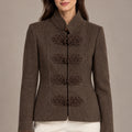 Front view of the brown Allegra Moro Toggle Jacket with a stand collar and decorative frog closures, worn with ivory trousers.