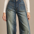 Close-up of Amber blue jeans showing the high waistband, button fastening and stitched front patch pockets.