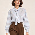 Close-up front view of a pale blue, white and almond striped shirt with a matching necktie.