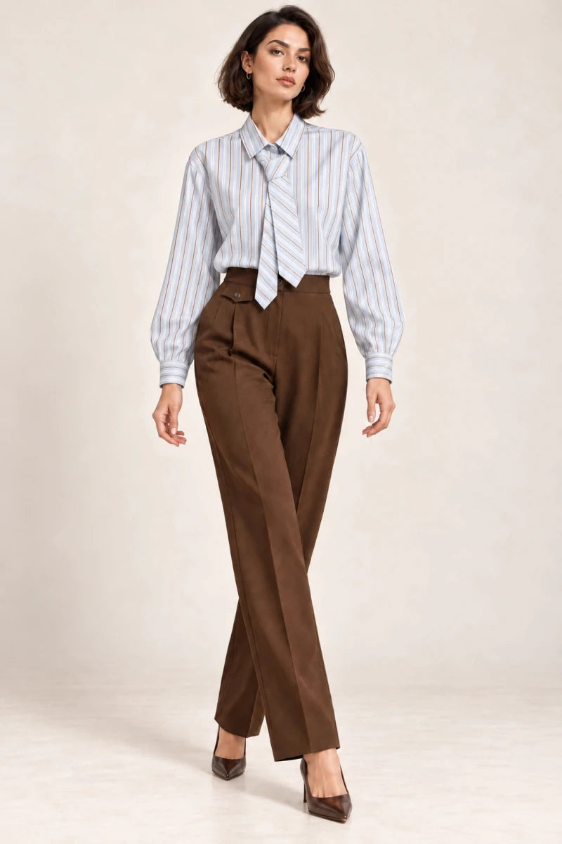 Full-length view of a model wearing a pale blue striped tie-neck shirt with brown tailored trousers.