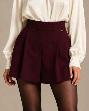 Close-up of Anima Bordeaux tailored skort showing the high waistband and front pleats.
