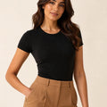 Black crew-neck short-sleeve top tucked into camel trousers, front view