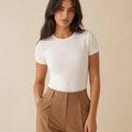 White crew-neck short-sleeve top tucked into camel trousers, front view