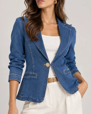 Close-up front view of a blue denim tailored blazer, showing its lapels, contrast stitching and welt pockets.