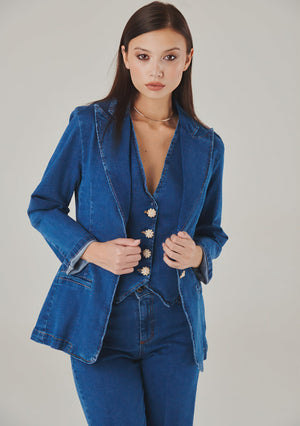 Front view of a blue denim tailored blazer worn open over a matching buttoned waistcoat and jeans.