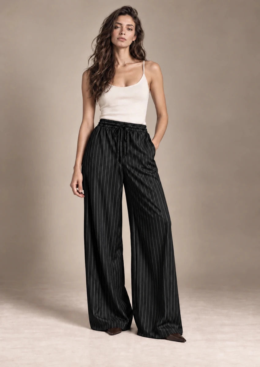 Full-length view of the Bridget black pinstripe wide-leg trousers styled with an ivory camisole.