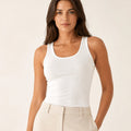 White longline tank top tucked into light tailored trousers, front view