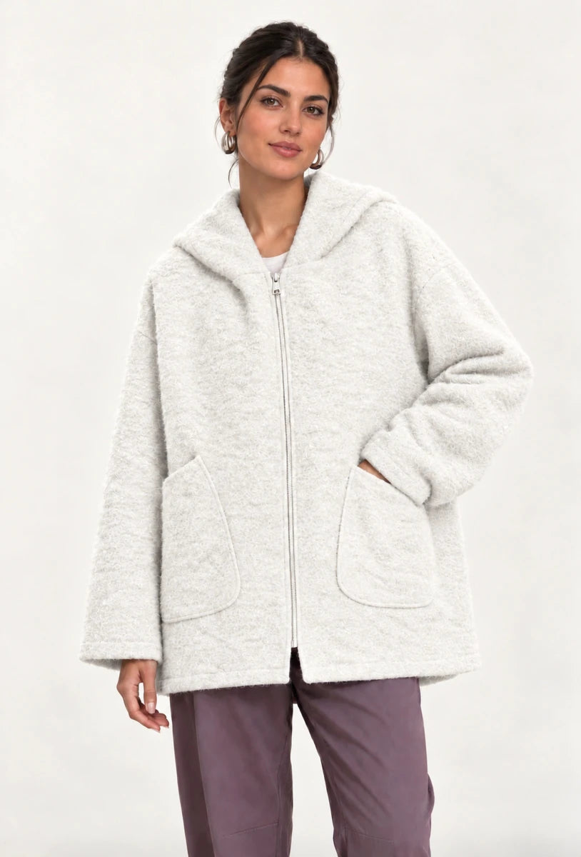 Front view of the cream Cappotto Oversize Panna with a hood, zip closure and large patch pockets, one hand in a pocket.