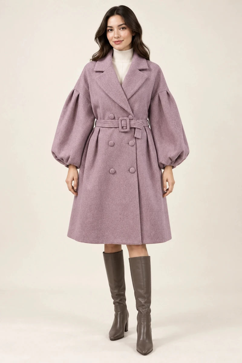 Front view of Cappotto Rosa Melange, a dusty pink double-breasted coat with puff sleeves and a matching buckle belt, worn with taupe knee-high boots.