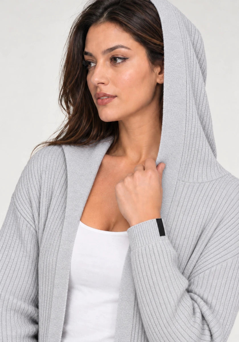 Close-up of a model wearing ELLY's grey ribbed cardigan with the hood raised, showing the ribbed sleeve and open front.