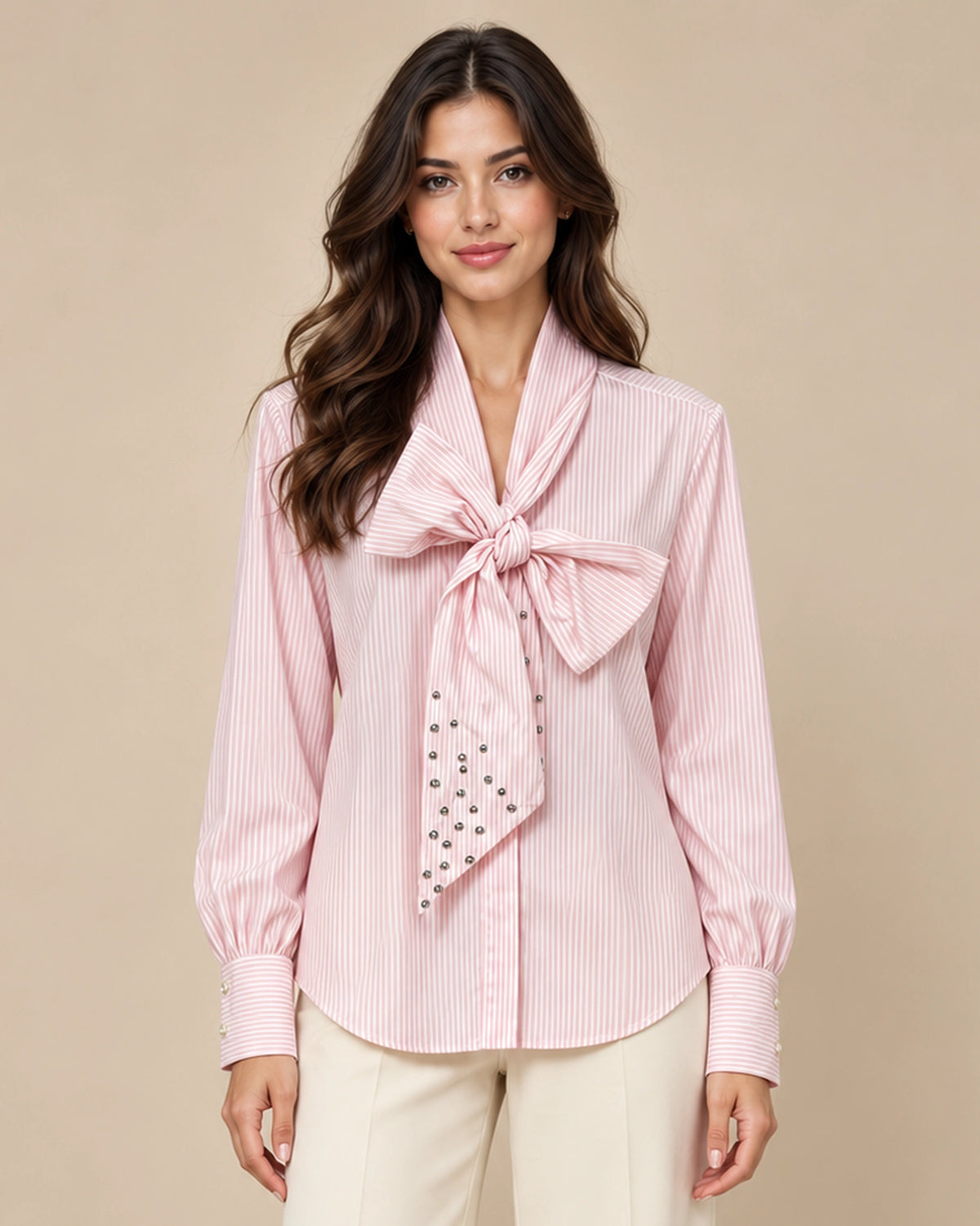 Close-up of the Carola pink striped shirt showing its large neck bow, long sleeves and wide cuffs.