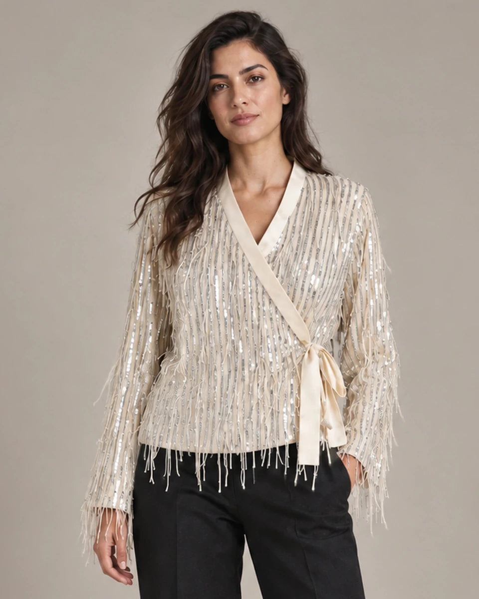 Close-up of the Cassandra Panna fringe wrap jacket showing its V-neck, side tie and hanging fringe, worn with black trousers.