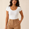 White scoop-neck cap-sleeve top tucked into camel trousers, front view