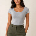 Grey scoop-neck cap-sleeve top tucked into olive trousers, front view