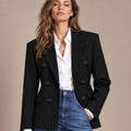 Close-up front view of the black pinstripe double-breasted blazer worn over a white shirt with blue jeans.