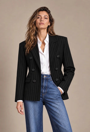 Front view of a model wearing the black pinstripe double-breasted blazer with a white shirt and blue jeans.