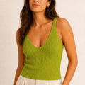 Woman wearing the ELLY lime green ribbed knit V-neck top with wide shoulder straps and ivory tailored trousers.