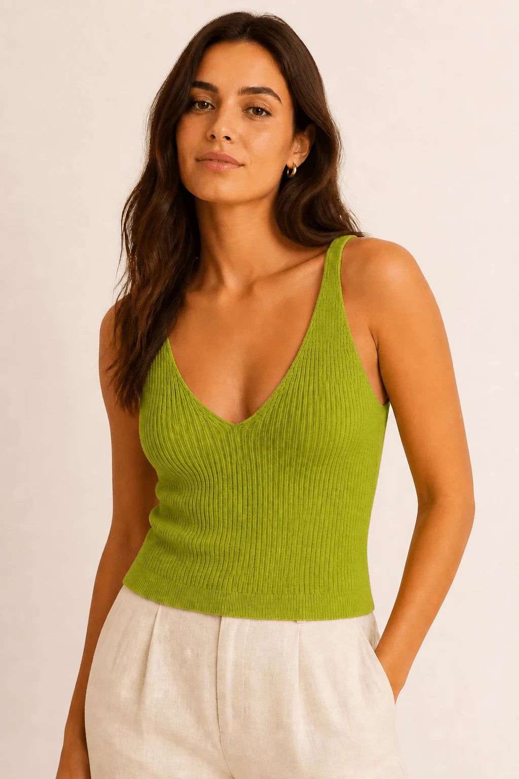 Woman wearing the ELLY lime green ribbed knit V-neck top with wide shoulder straps and ivory tailored trousers.