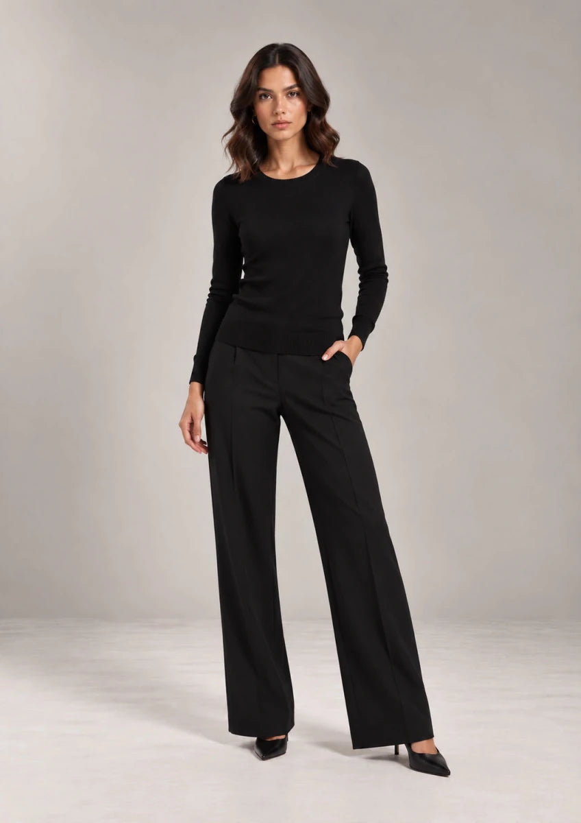 Full-length view of a model wearing the black Livia crew-neck knit top with black wide-leg trousers.