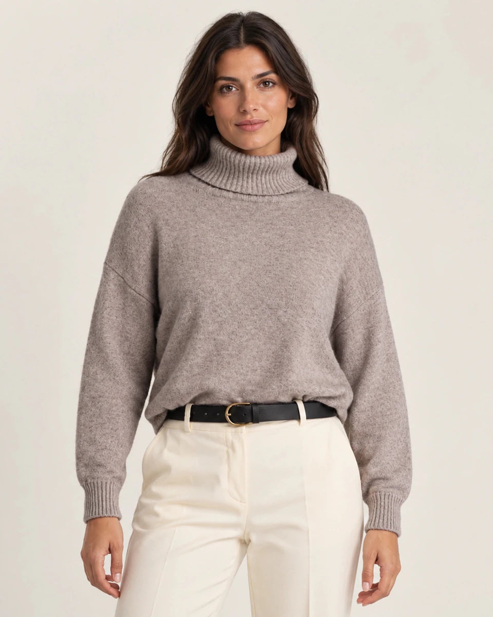 Front view of Maglia Collo Alto Greige sweater with a ribbed turtleneck and cuffs, worn with cream trousers