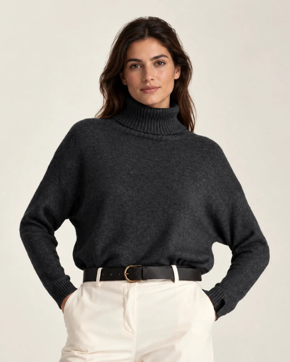 Front view of Maglia Collo Alto Nero dark knit sweater with a ribbed turtleneck and cuffs, worn with cream trousers