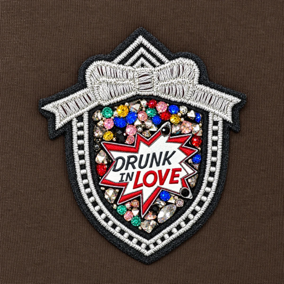 Close-up of the embellished badge on Leila Moro track jacket, with colourful stones and the words “DRUNK IN LOVE”.