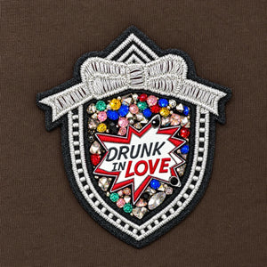 Close-up of the embellished badge on Leila Moro track jacket, with colourful stones and the words “DRUNK IN LOVE”.