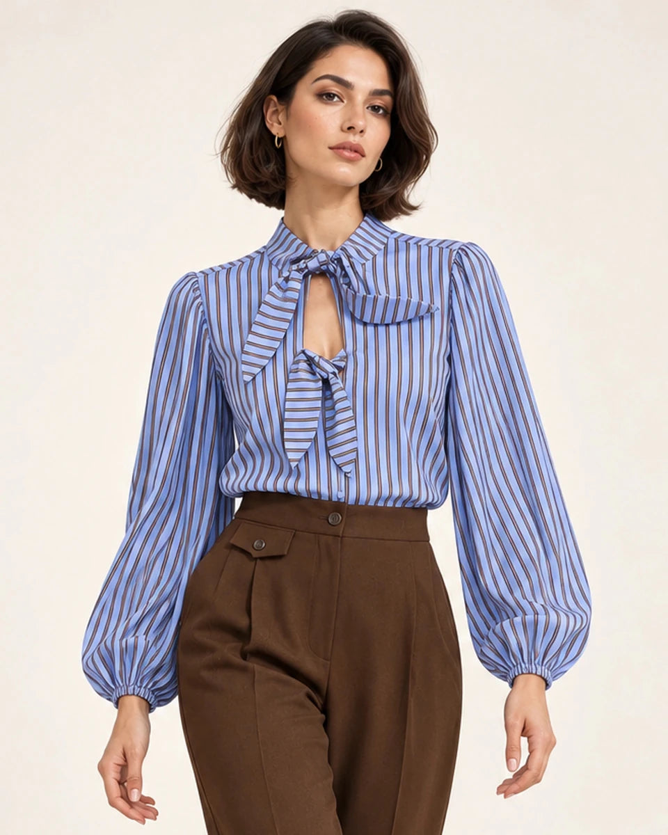 Close-up front view of a blue and brown striped shirt with bow ties and gathered long sleeves, worn with brown trousers.