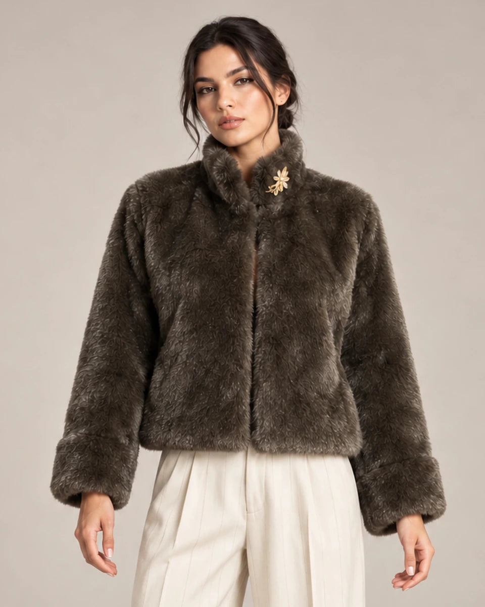 Close-up of the brown Mora Moro plush jacket showing its raised collar, long sleeves and wide cuffs, styled with ivory trousers.