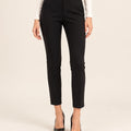 Front detail of black tailored ankle-length trousers showing the waistband and tapered legs, with arms at the sides.