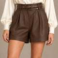Close-up front view of brown leather-look shorts with front pleats, a matching belt and a star charm.